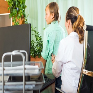 A doctor feels around a young teenagers lower back